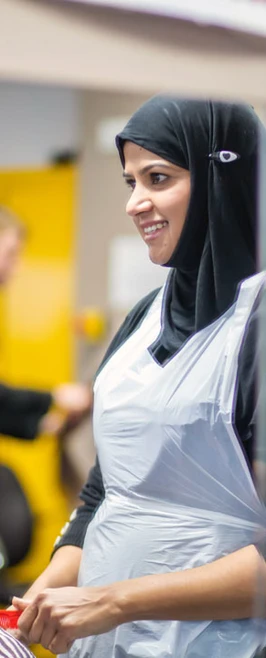 Hairstyling student in a hijab styling a client's hair in a salon. Hairstyling student in a hijab styling a client's hair in a salon.